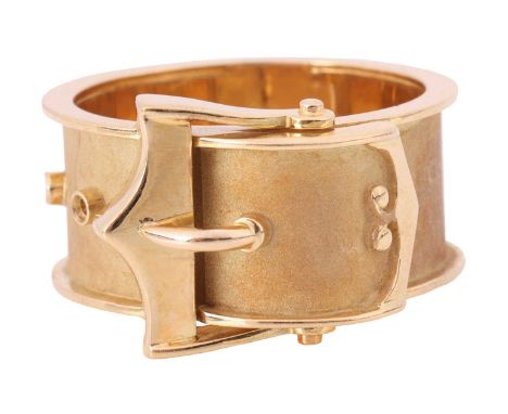 A dress ring in the form of a belt buckle, flat band with sandblast finish and polished trims, yellow metal stamped '18ct' an