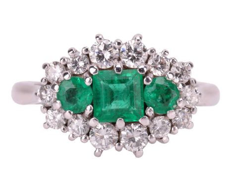An emerald and diamond cluster ring in 18ct white gold, the navette-shaped ring head centred with a step-cut emerald flanked 