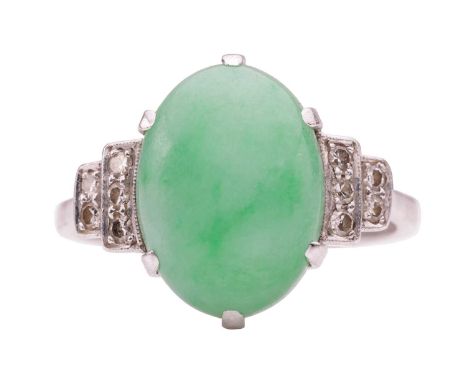 An Art Deco style jade and diamond dress ring, centred with an oval jadeite cabochon of 13.2 x 9.8 x 5.1 mm, claw-set between