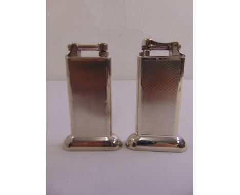 Two Dunhill rectangular engine turned table lighters on raised oval bases