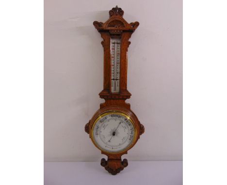 A carved oak cased banjo aneroid barometer and thermometer with white enamel dials and brass bezel