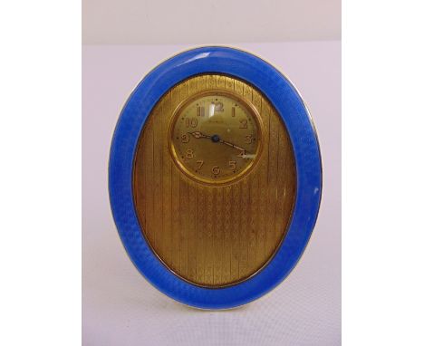 A Sampson and Morden Co. silver and enamel oval boudoir clock, engine turned, circular dial with Arabic numerals with hinged 