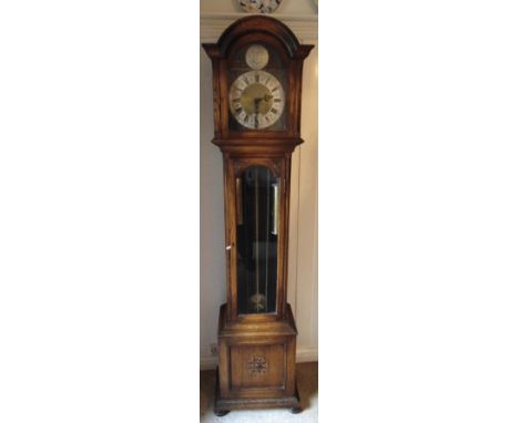 An oak longcase clock with silvered dial with Roman numerals, hinged glazed case on four bun feet by Bravingtons of London to