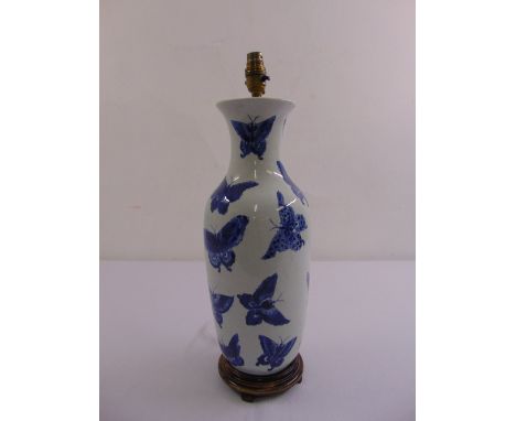 A Chinese blue and white baluster vase converted to a table lamp decorated with butterflies, mounted on raised circular woode