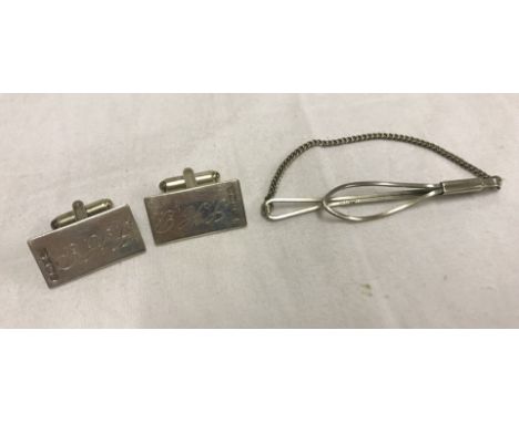 A pair of monogrammed silver cufflinks, hallmarked Birmingham 1977. Together with a silver tie clip. 