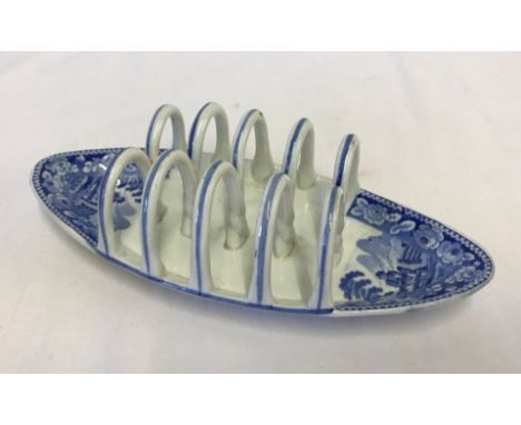 A blue and white toast rack, unknown maker with rural pattern depicting a man stood at a gate.  Approx. 24cm long.