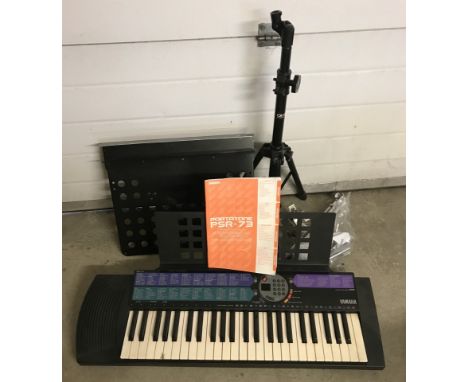 A Yamaha Portatone PSR-73 electronic keyboard with power adapter and instruction manual. Together with an assortment of stand