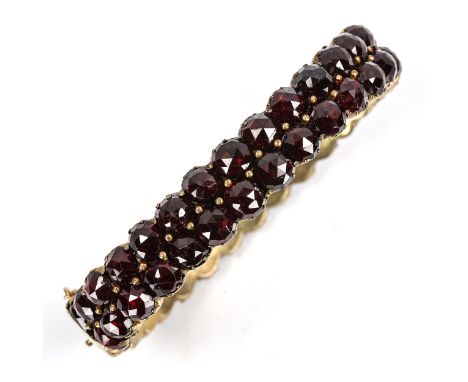 A Victorian Bohemian faceted garnet bangle, unmarked yellow metal settings, band width 10.9mm, internal dimensions 5.2cm x 4.
