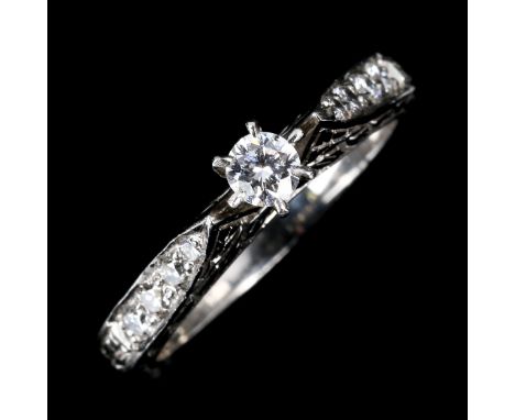 A modern platinum solitaire diamond ring, 6-claw setting with diamond set shoulders and engraved bridge and shank, total diam