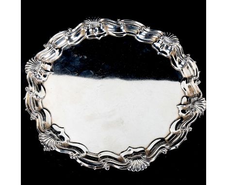 An Edwardian silver salver, with cast foliate and shell rim, and claw and ball feet, by Goldsmiths & Silversmiths Co Ltd, hal