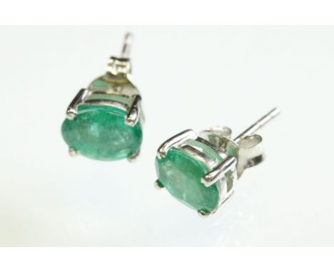 Pair of emerald silver stud earrings, the oval mixed cut emerald measuring approx 8mm x 6mm, claw set, post and butterfly ear