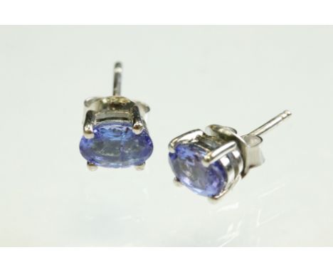 Pair of tanzanite silver stud earrings, the oval mixed cut tanzanite measuring approx 7mm x 5mm, claw set, post and butterfly