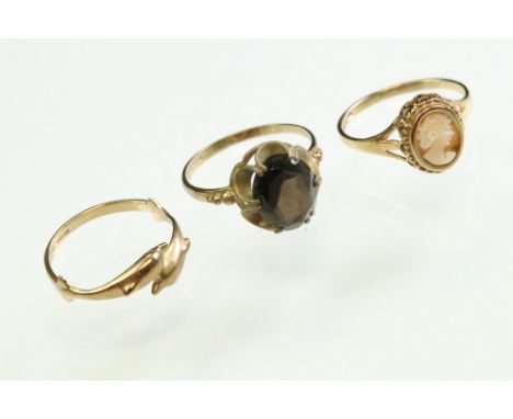 Smoky quartz 9ct yellow gold ring; shell cameo 9ct yellow gold ring; and a 9ct yellow gold dolphin ring (3) 