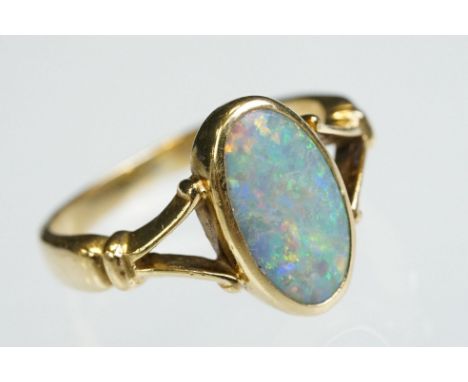 Opal 18ct yellow gold ring, the oval cabochon cut previous white opal displaying violet, blue, yellow, green, orange and red 