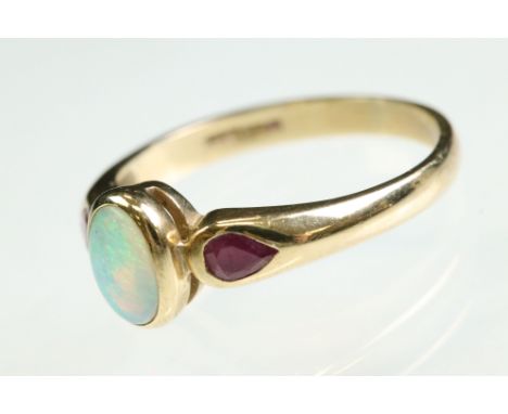 Opal and ruby 9ct yellow gold ring, the oval precious white oval opal displaying violet, yellow, green and orange play of col