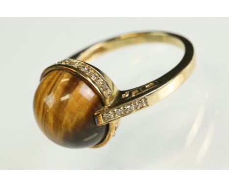 Tigers' eye and diamond 9ct yellow gold ring, the circular cabochon cut tigers' eye diameter approx 11.5mm, rubover set, smal