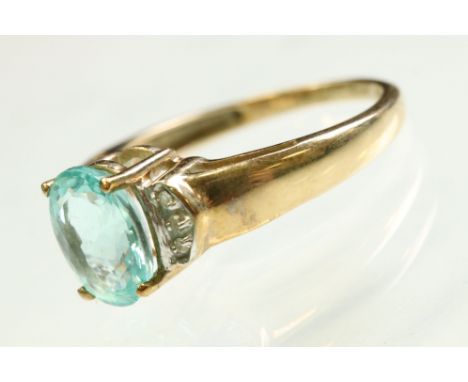 Topaz and diamond 9ct yellow gold ring, the central oval mixed cut blue topaz measuring approx 9mm x 7mm, claw set, three sma