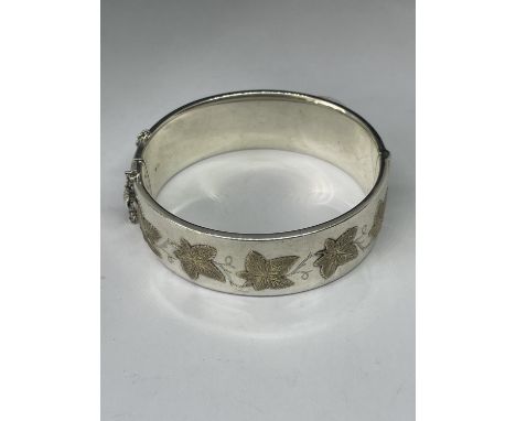 A HALLMARKED BIRMINGHAM 1940 CHARLES S GREEN &amp; CO SILVER BANGLE EMBOSSED WITH GOLD LEAVES GROSS WEIGHT 58.8 GRAMS 