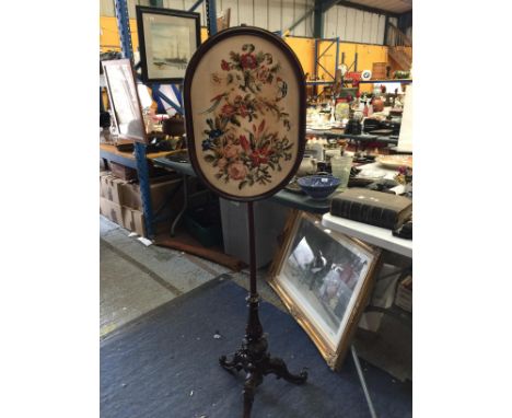 A TAPESTRY SCREEN ON A POLE WITH CARVED TRIPOD LEGS 