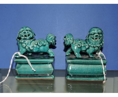 A pair of turquoise glazed ceramic dogs of Fo, raised on shaped rectangular bases, H. 10cm.