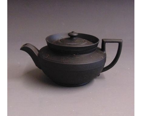 A Wedgwood black basalt teapot and cover, engine turned with a turreted collar, glazed insidelate 19th Century, impressed WED