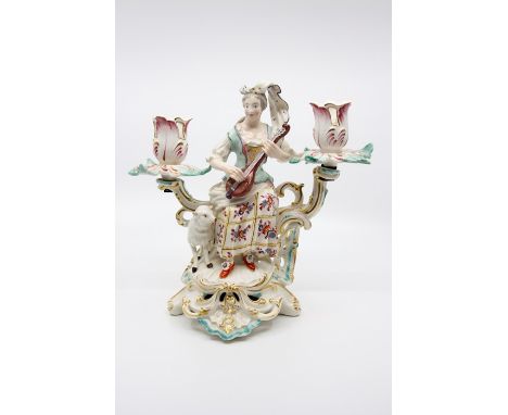 A Derby porcelain candelabrum, circa 1760-65, modelled as a shepherdess with lute and lamb, on Rococo scroll base, twin branc