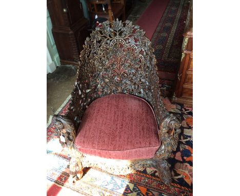 A late 19th Century Chinese hand carved high backed tub chair, elaborately carved throughout with foliage, the arm terminals 