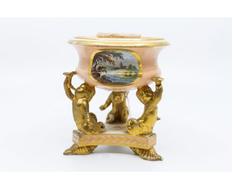 A Derby porcelain tripod inkwell, circa 1805, the squat ogee campana body painted with a view of a church on riverbank, suppo