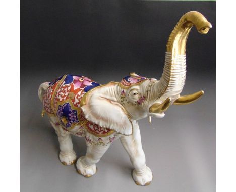 A large decorative Capo di Monte porcelain model of a standing  elephant with trunk up, ivory ground decorated in red, blue a