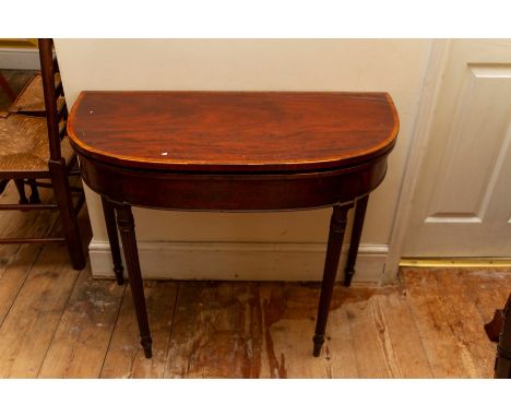 A George III mahogany demi-lune shaped card table,&nbsp;standing on turned tapered legs