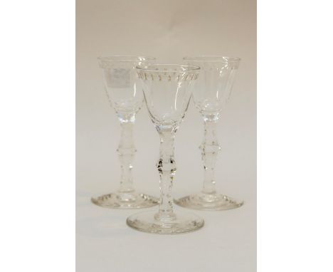 A set of three George III style wine glasses, rounded bowls with star and lens border, on faceted stems and conical feet, pol