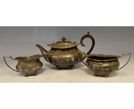 A George VI silver three piece tea set comprising teapot, sugar bowl and milk jug, oval shaped with fluted sections with acan