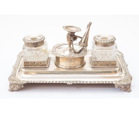 An Edwardian silver desk stand, rectangular tray form with gadrooned border and foliate bracket feet, two floral bordered com