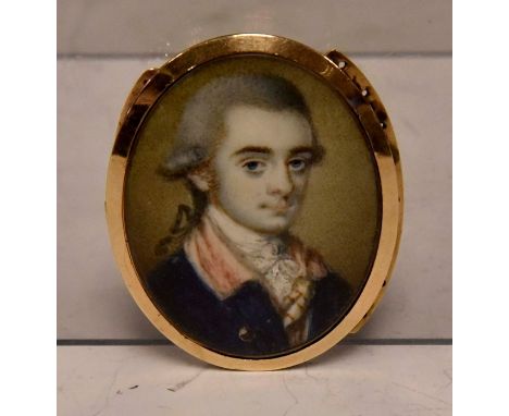 A George III oval portrait miniature of a young dandy, wearing  white stock and a blue tunic, on ivory, set in a yellow metal