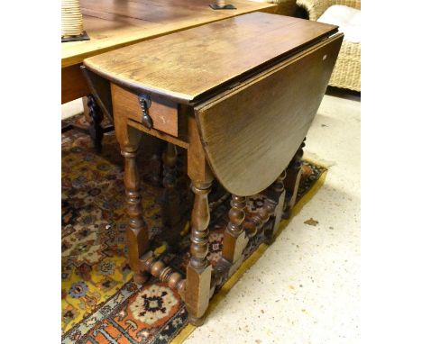 A small oak drop leaf table with end drawer and gate-leg turned supports