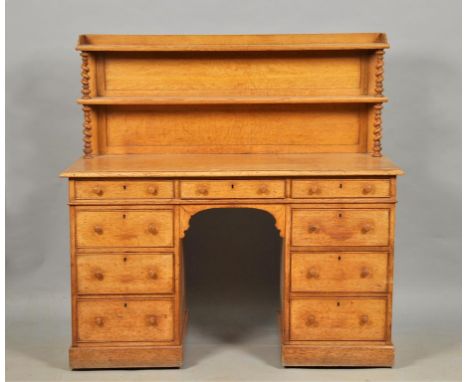 A Victorian oak pedestal desk with raised panel back bookshelves, having twist carved supports, on a base with one central dr