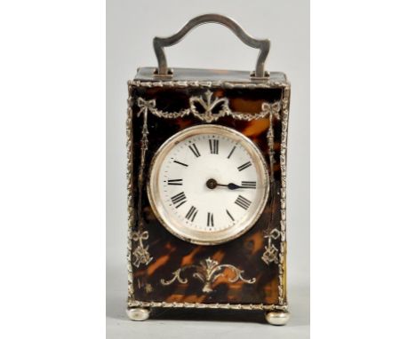 A tortoiseshell desk clock with silver swag and ribbon decoration within silver borders, having central carrying handle and s