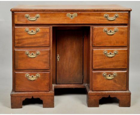 A George III mahogany kneehole desk of rectangular form with moulded edge and rounded corners, crossbanded and having one lon