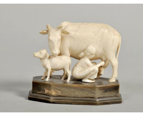 A late 19c Indian ivory figure group carved as a lady milking a cow, the cow with a calf at foot, on a horn base, 4 x 3.5.