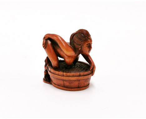A signed carved erotic fruitwood netsuke of a young woman and a frog.
