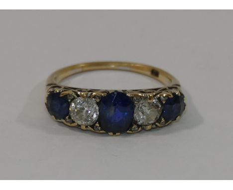 An 18 carat gold sapphire and diamond five stone carved half hoop ring, the central cushion shaped mixed cut sapphire approxi