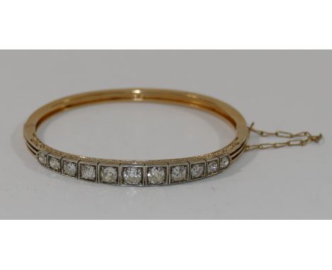 A diamond set hinged gold bangle, the eleven old round brilliant cut diamonds in individual graduated white box settings, the