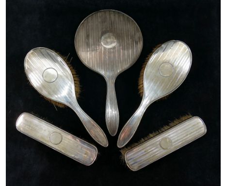 A five piece silver backed brush and mirror set, Birmingham 1923 and 1925, comprised of two pairs of brushes and a mirror, wi