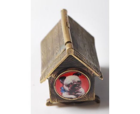 A vintage style brass vesta case in the form of a kennel with an enamel pugs face to the front. Strike plate to the bottom.&n