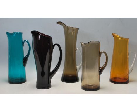 A collection of five retro 1970s vintage studio art glass Whitefriars water pitchers / jugs in Kingfisher Blue, Ruby Red, Smo