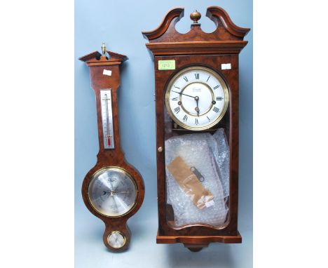 A Comitti of London mahogany wall clock having a finial top flanked by a pediment top. Clock comes with pendulum and key. Tog