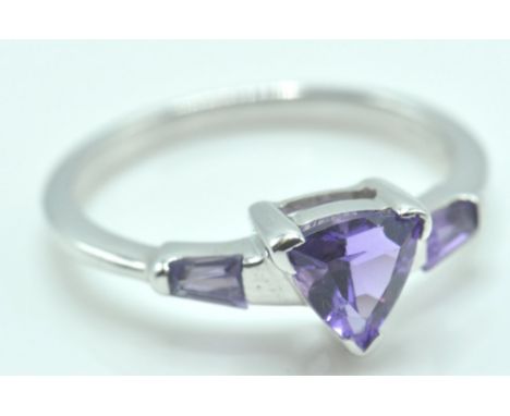 A 9ct white gold ring set with a central triangle cut purple stone flanked by two further stones to the shoulders Stamped 375