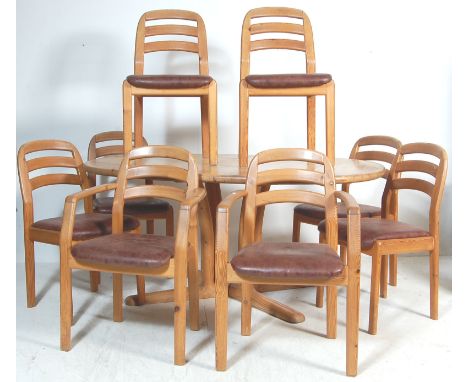 A late 20th century vintage extending pine dining table and 8 chairs. The table has an oval table top raised on splayed suppo