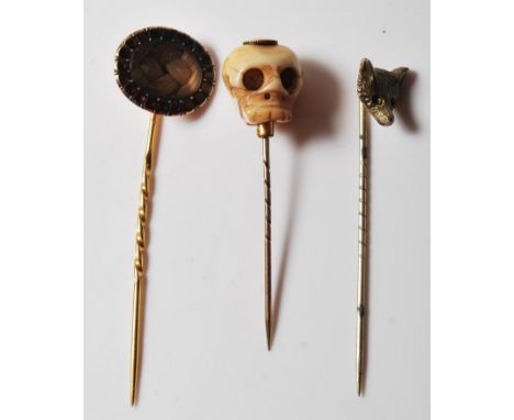 A group of three 19th Century antique stick pins to include a carved bone stick pin with a skull finial, a braided hair mourn