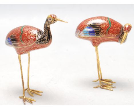 A pair of 20th century Chinese oriental Beijing cloisonné / cloisonne cranes being decorated with red, black and blue enamel 